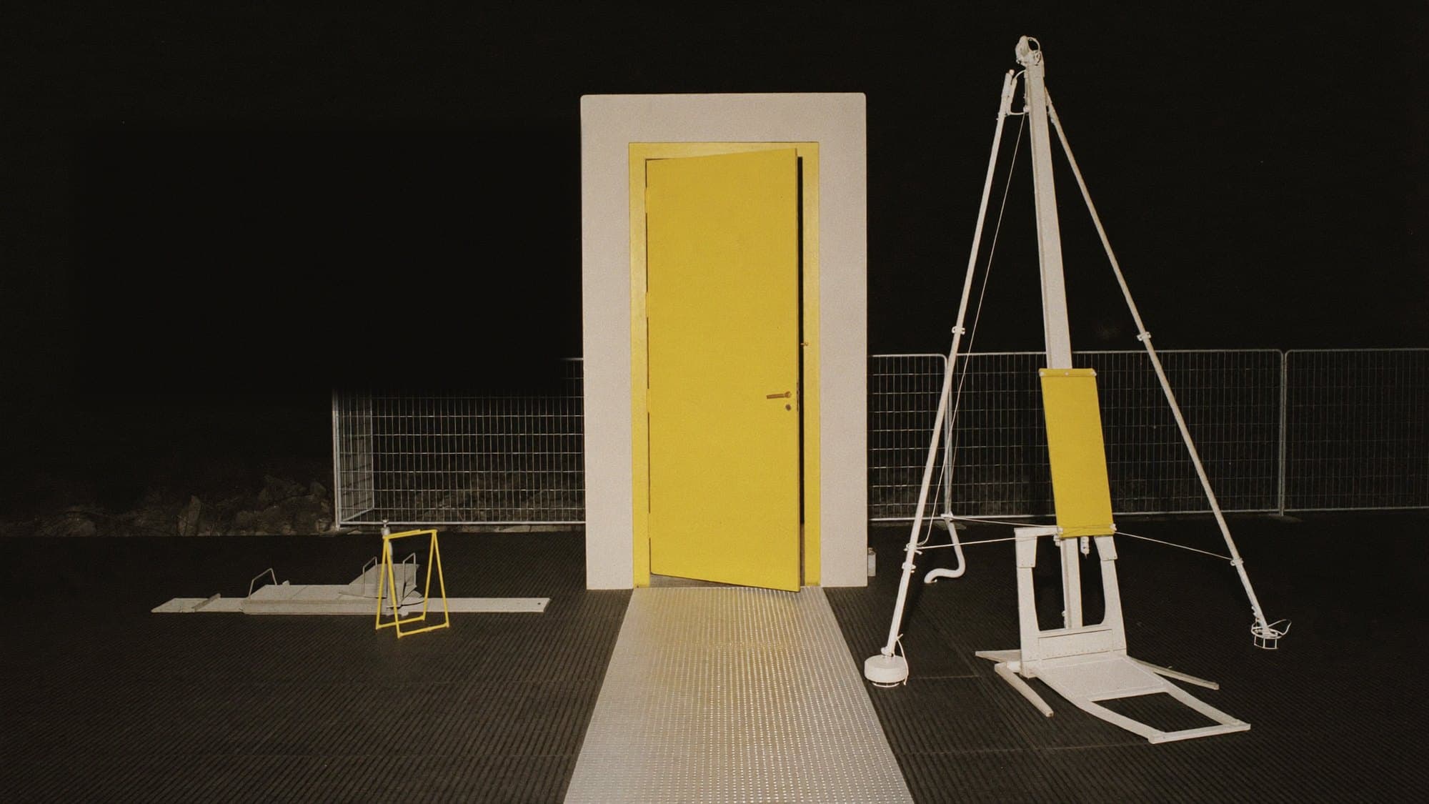 A freestanding yellow door at night with the Drop 001 objects arranged around it