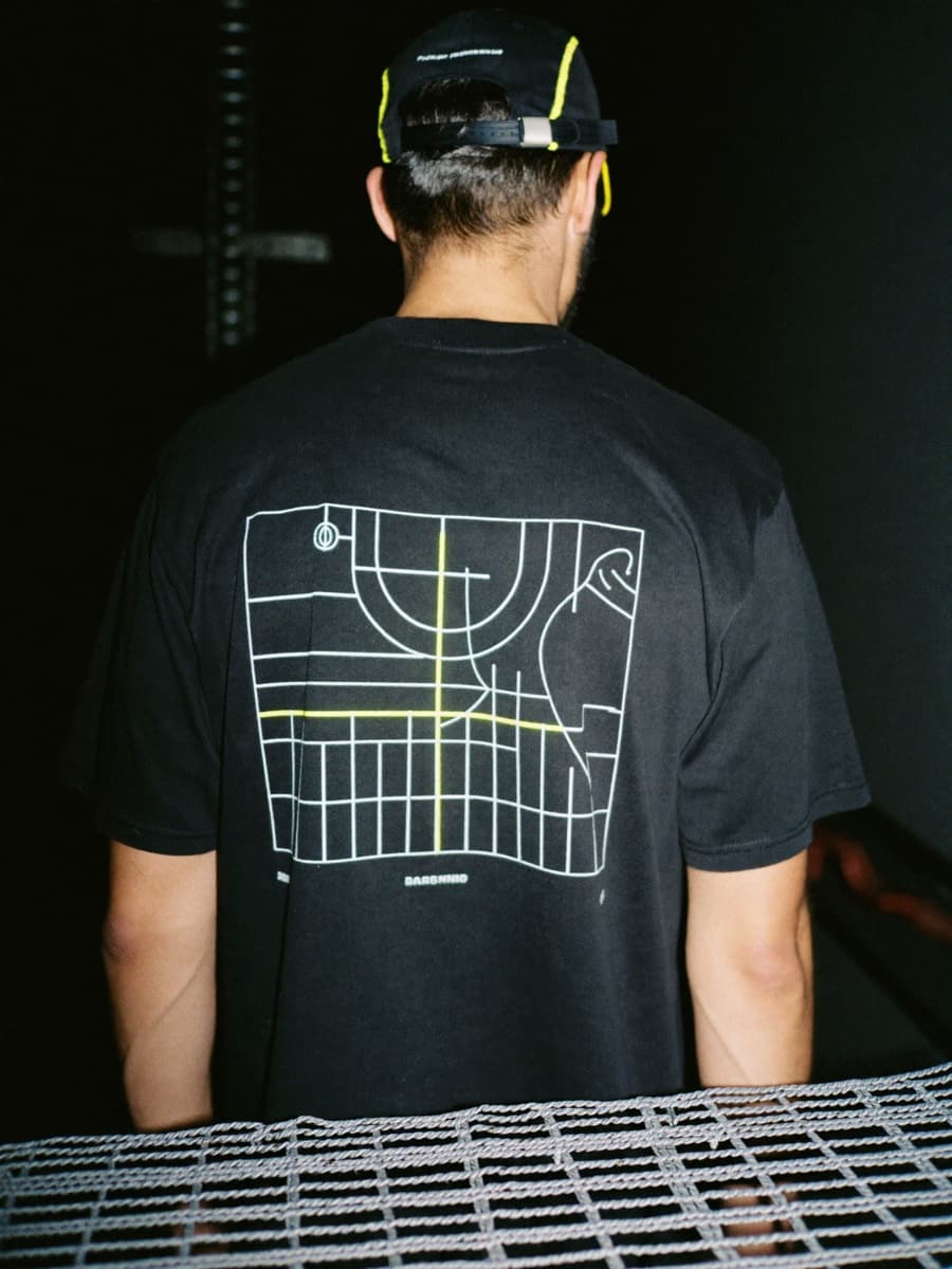 The After Hours uniform - black tee and cap on a fencing piste at night